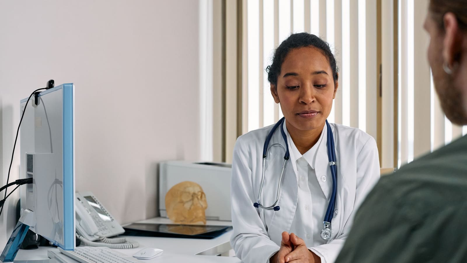 A pain medicine physician talks through treatment options with a patient across a desk at a clinic consultation.